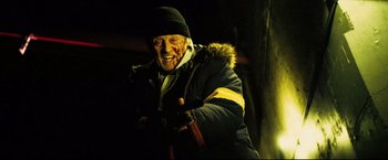 Movie still from “Hobo with a Shotgun” (2011), directed by Jason Eisener – An old man with a beard and a hat and jacket on; Medium shot, High angle