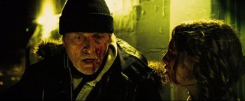 Movie still from “Hobo with a Shotgun” (2011), directed by Jason Eisener – A man in a black jacket and a man in a black hat; Close Up shot, Over the shoulder angle