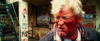 Movie still from “Hobo with a Shotgun” (2011), directed by Jason Eisener – A man with blood all over his face; Close Up shot, Low angle