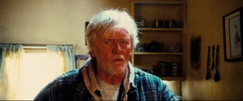 Movie still from “Hobo with a Shotgun” (2011), directed by Jason Eisener – An older man with white hair is looking at the camera; Close Up shot, Low angle