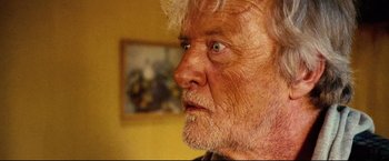 Movie still from “Hobo with a Shotgun” (2011), directed by Jason Eisener – An older man with white hair looking into the distance; Close Up shot, Over the shoulder angle