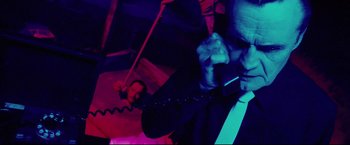 Movie still from “Hobo with a Shotgun” (2011), directed by Jason Eisener – A man in a suit is on the phone; Medium shot, Low angle