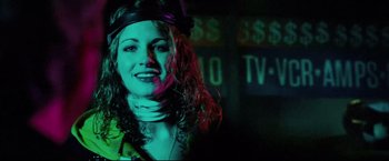 Movie still from “Hobo with a Shotgun” (2011), directed by Jason Eisener – A woman in a green jacket is smiling for the camera; Close Up shot, Low angle