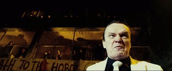 Movie still from “Hobo with a Shotgun” (2011), directed by Jason Eisener – A person wearing a suit and tie; Close Up shot, Low angle