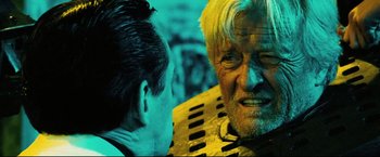 Movie still from “Hobo with a Shotgun” (2011), directed by Jason Eisener – An old man with a beard and a man with a mustache; Close Up shot, Over the shoulder angle