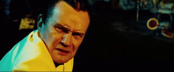 Movie still from “Hobo with a Shotgun” (2011), directed by Jason Eisener – An older man in a yellow shirt and a yellow tie; Close Up shot, Low angle