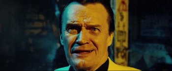 Movie still from “Hobo with a Shotgun” (2011), directed by Jason Eisener – An older man in a yellow jacket looking at the camera; Close Up shot, Low angle