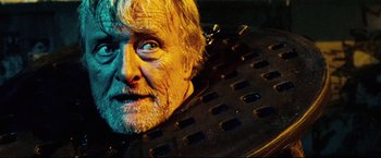 Movie still from “Hobo with a Shotgun” (2011), directed by Jason Eisener – An old man with a beard and mustache is looking at the camera; Close Up shot, Overhead angle