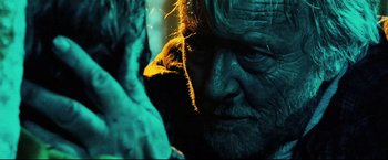 Movie still from “Hobo with a Shotgun” (2011), directed by Jason Eisener – An old man with a long beard is looking at the camera; Close Up shot, Over the shoulder angle