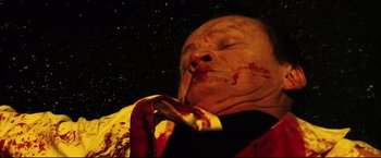 Movie still from “Hobo with a Shotgun” (2011), directed by Jason Eisener – A man with blood all over his face smoking a cigarette in front of a star filled sky; Close Up shot, Overhead angle