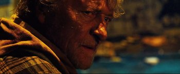 Movie still from “Hobo with a Shotgun” (2011), directed by Jason Eisener – An older man with a beard and mustache; Close Up shot, Over the shoulder angle