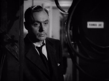 Movie still from “Hold Back the Dawn” (1941), directed by Mitchell Leisen – A man wearing a suit and tie standing in front of a camera; Close Up shot, Low angle