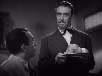 Movie still from “Hold Back the Dawn” (1941), directed by Mitchell Leisen – A man holding a plate of food in front of another man; Medium shot, Low angle