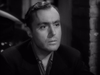 Movie still from “Hold Back the Dawn” (1941), directed by Mitchell Leisen – A man in a suit and tie sitting in a room; Close Up shot, Low angle