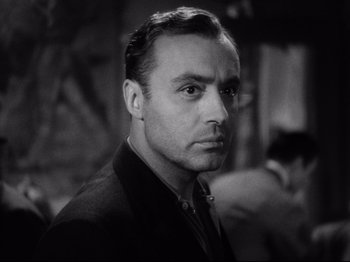 Movie still from “Hold Back the Dawn” (1941), directed by Mitchell Leisen – A man in a black jacket is looking at the camera; Close Up shot, Low angle