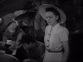 Movie still from “Hold Back the Dawn” (1941), directed by Mitchell Leisen – A woman wearing a white dress and a white hat; Medium shot, High angle