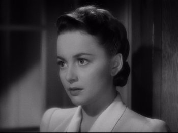 Movie still from “Hold Back the Dawn” (1941), directed by Mitchell Leisen – A black - and - white photo of a woman in a suit; Close Up shot, Over the shoulder angle