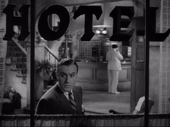 Movie still from “Hold Back the Dawn” (1941), directed by Mitchell Leisen – A black and white photo of a man in a suit and tie in front of a hotel sign; Medium shot, Low angle