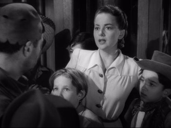Movie still from “Hold Back the Dawn” (1941), directed by Mitchell Leisen – A woman standing in front of a group of people; Medium shot, High angle