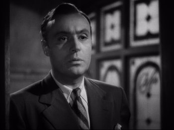 Movie still from “Hold Back the Dawn” (1941), directed by Mitchell Leisen – A man wearing a suit and tie standing in front of a wall; Close Up shot, Low angle