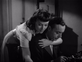 Movie still from “Hold Back the Dawn” (1941), directed by Mitchell Leisen – A man and a woman hugging each other in front of a computer screen; Medium shot, Overhead angle