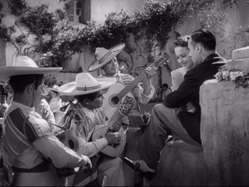 Movie still from “Hold Back the Dawn” (1941), directed by Mitchell Leisen – A group of men sitting on the side of a building; Wide shot, High angle