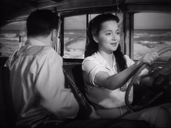 Movie still from “Hold Back the Dawn” (1941), directed by Mitchell Leisen – A woman sitting in the driver's seat of a bus while a man sits in the passenger seat; Medium shot, High angle