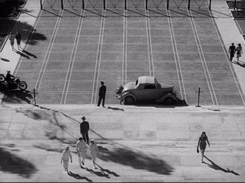 Movie still from “Hold Back the Dawn” (1941), directed by Mitchell Leisen – An old car parked in the middle of a parking lot; Extreme Wide shot, Overhead angle