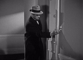 Movie still from “Holiday” (1938), directed by George Cukor – A black and white photo of a man wearing a hat; Medium shot, High angle