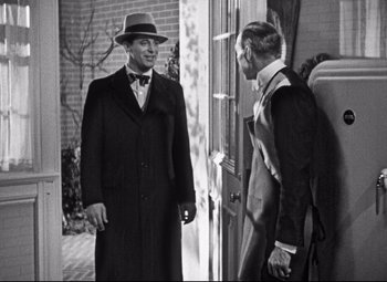 Movie still from “Holiday” (1938), directed by George Cukor – A man in a hat and a suit standing next to another man in a suit; Medium shot, Over the shoulder angle