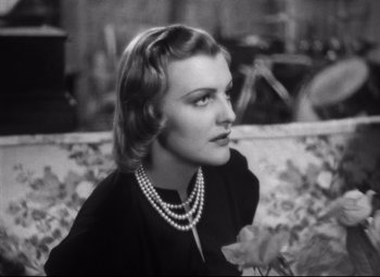 Movie still from “Holiday” (1938), directed by George Cukor – A black and white photo of a woman wearing a pearl necklace; Close Up shot, Over the shoulder angle