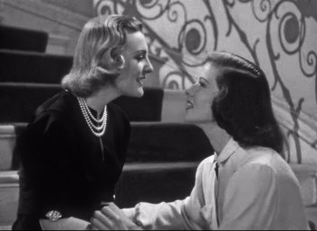 Movie still from “Holiday” (1938), directed by George Cukor – Two women are shaking hands in front of each other; Medium shot, Low angle