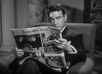 Movie still from “Holiday” (1938), directed by George Cukor – A black and white photo of a man sitting on a couch reading a newspaper; Close Up shot, Low angle