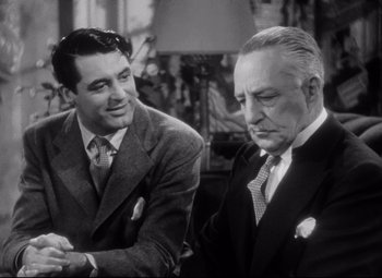 Movie still from “Holiday” (1938), directed by George Cukor – A man and a man sitting next to each other in front of a lamp; Close Up shot, Over the shoulder angle