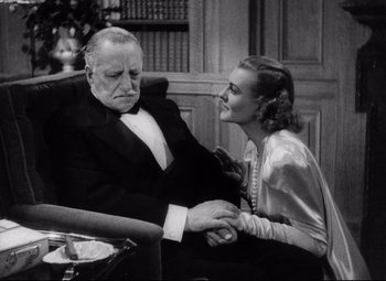 Movie still from “Holiday” (1938), directed by George Cukor – An older man sitting next to an older woman holding hands; Medium shot, High angle