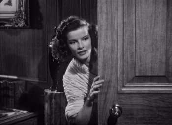 Movie still from “Holiday” (1938), directed by George Cukor – A black - and - white photo of a woman peeking through a door; Medium shot, High angle