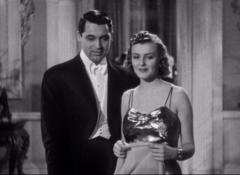 Movie still from “Holiday” (1938), directed by George Cukor – A man and a woman standing next to each other in formal wear; Medium shot, Low angle