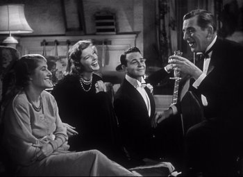 Movie still from “Holiday” (1938), directed by George Cukor – A black and white photo of a group of people drinking champagne; Medium shot, Low angle