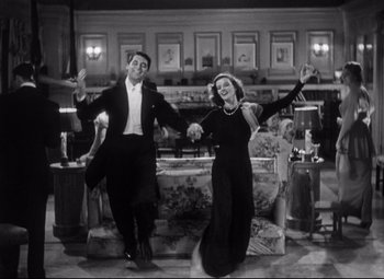 Movie still from “Holiday” (1938), directed by George Cukor – A man and a woman holding hands while standing in a living room; Wide shot, Low angle