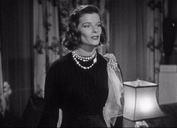 Movie still from “Holiday” (1938), directed by George Cukor – A black and white photo of a woman wearing a dress; Close Up shot, Over the shoulder angle