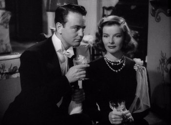 Movie still from “Holiday” (1938), directed by George Cukor – A man and a woman standing next to each other holding wine glasses; Medium shot, Low angle
