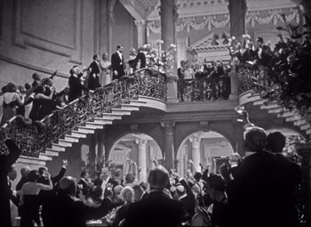 Movie still from “Holiday” (1938), directed by George Cukor – A group of people standing on top of a set of stairs; Extreme Wide shot, High angle