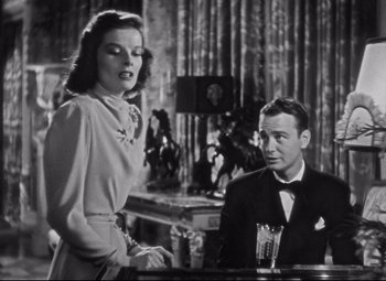 Movie still from “Holiday” (1938), directed by George Cukor – A man and a woman sitting at a table in a room; Medium shot, Low angle