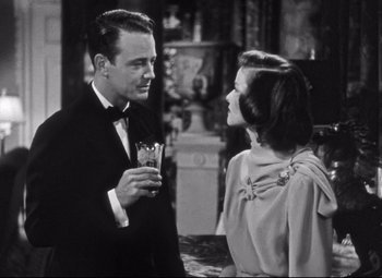Movie still from “Holiday” (1938), directed by George Cukor – A man and a woman standing next to each other holding drinks; Medium shot, Over the shoulder angle