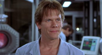 Movie still from “Hollow Man” (2000), directed by Paul Verhoeven – Kevin bacon in a blue shirt in front of some people; Close Up shot, Low angle