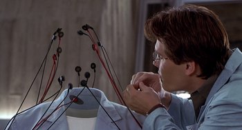 Movie still from “Hollow Man” (2000), directed by Paul Verhoeven – A man is working with wires in a room; Close Up shot, Overhead angle