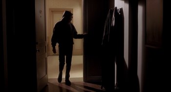 Movie still from “Hollow Man” (2000), directed by Paul Verhoeven – A man in a hooded jacket opening the door of a room; Wide shot, Low angle