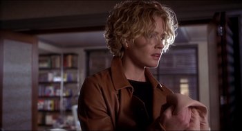 Movie still from “Hollow Man” (2000), directed by Paul Verhoeven – A woman with blonde curly hair wearing a brown jacket; Close Up shot, Over the shoulder angle