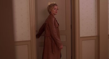 Movie still from “Hollow Man” (2000), directed by Paul Verhoeven – A woman standing in front of a door wearing a brown coat; Medium shot, High angle