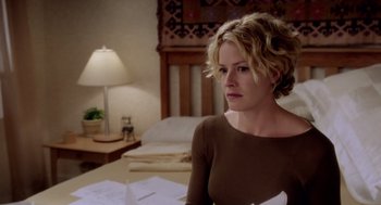 Movie still from “Hollow Man” (2000), directed by Paul Verhoeven – A woman sitting at a table in front of a lamp; Medium shot, Over the shoulder angle